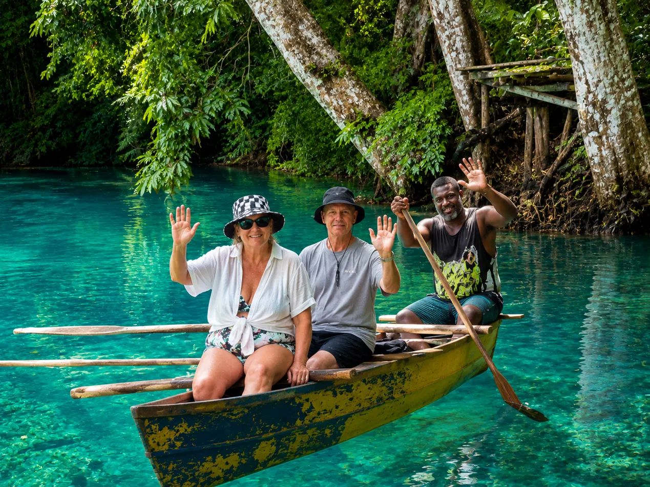 Guests travelling by traditional canoe on the Riri River with a local guide paddling